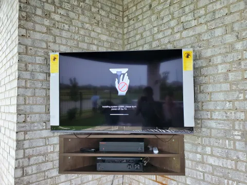 Outdoor patio TV mounted on brick with media shelf